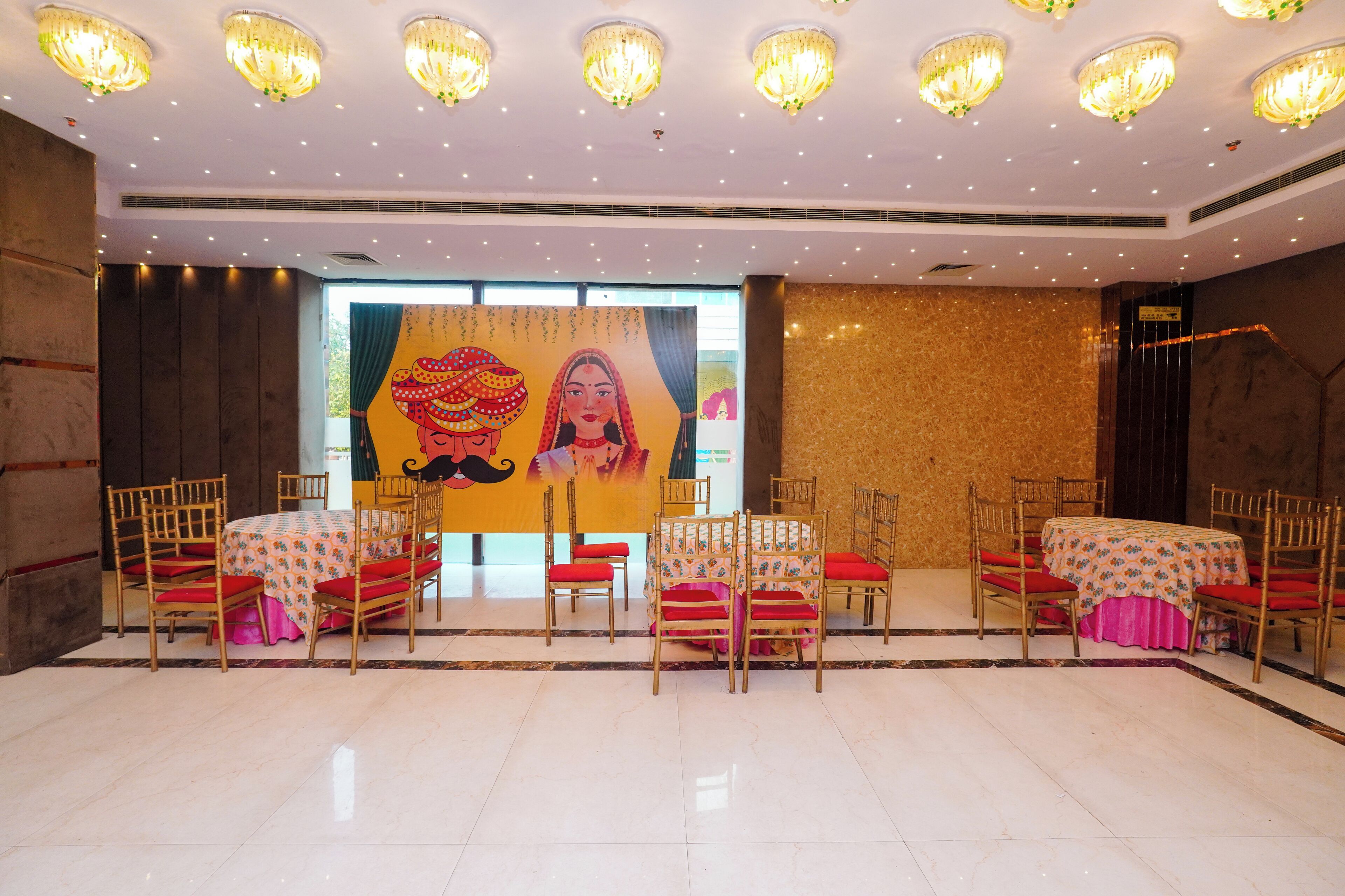 Une salle de banquet avec des tables rondes, des chaises rouges et des lustres.