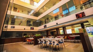 A multi-level atrium with glass railings, dining tables, and chairs. - Krishna Valley Wellness Resort Vrindavan (Mathura)