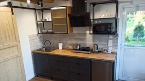 Ett modernt kök med en bänkskiva i trä, rostfria vitvaror och mörka köksskåp.