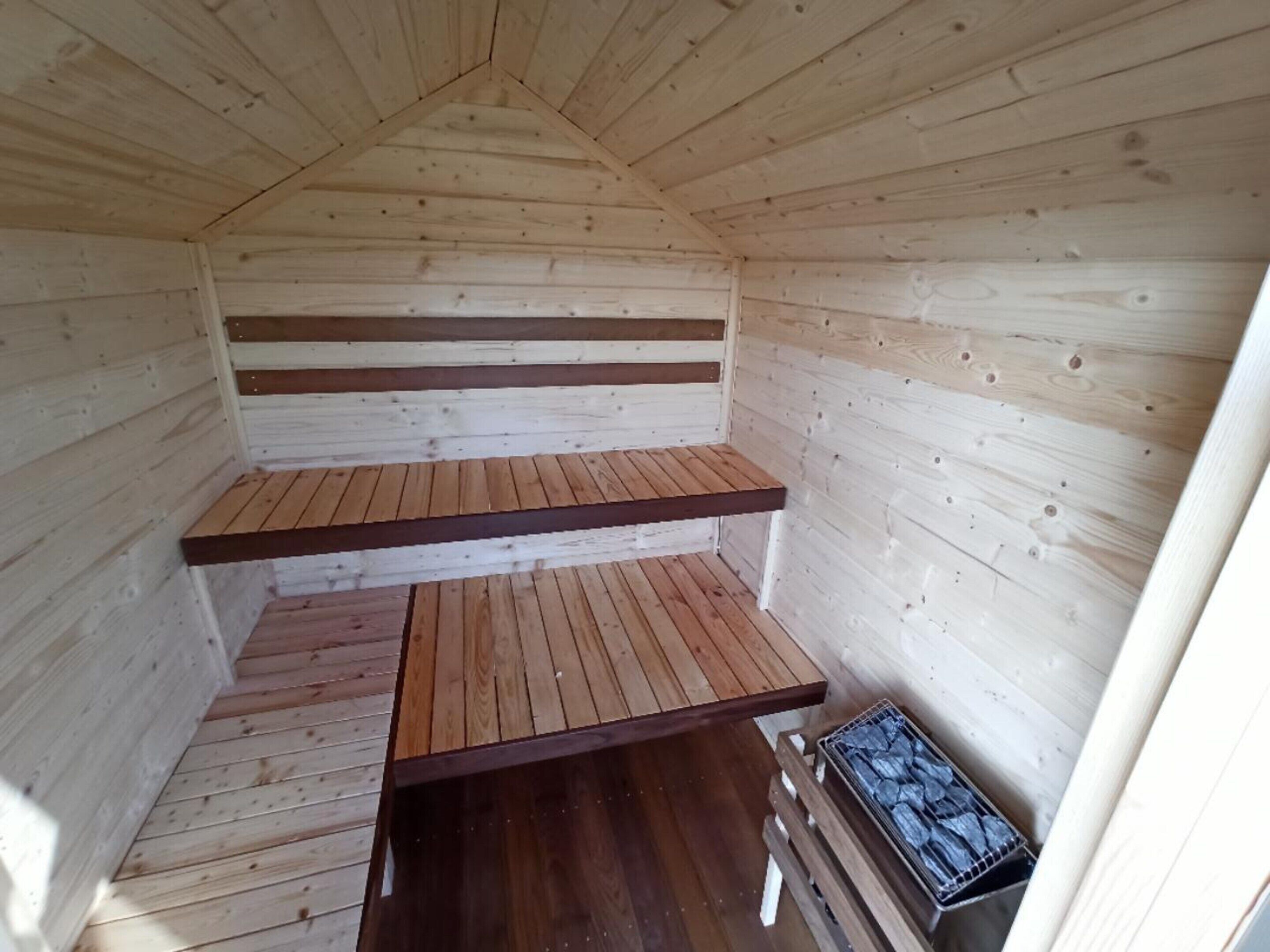 A wooden cabin with a sloped ceiling and two wooden benches.