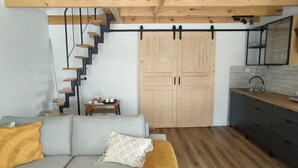 En modern inredning med en trappa, en soffa, ett köksområde och en skjutdörr.