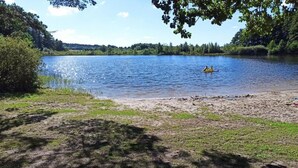 En stilla sjö med en kajak i fjärran, omgiven av grönska och träd.