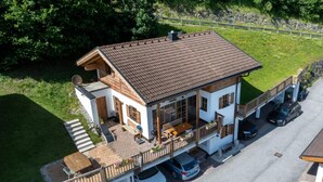 Une maison à deux étages avec un balcon, un abri pour voiture et une allée.