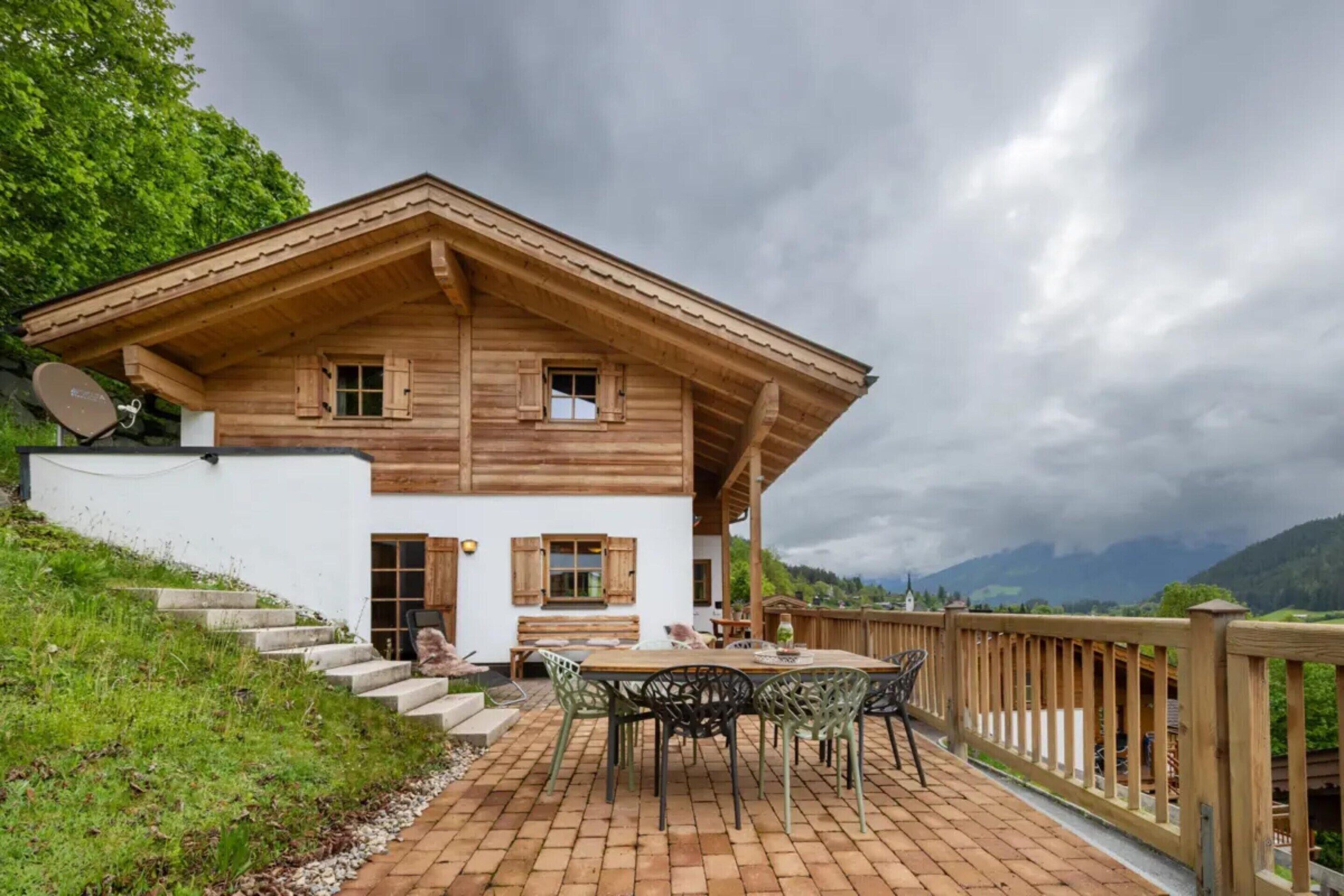 Una cabaña de madera con balcón, mobiliario exterior y vistas a las montañas.