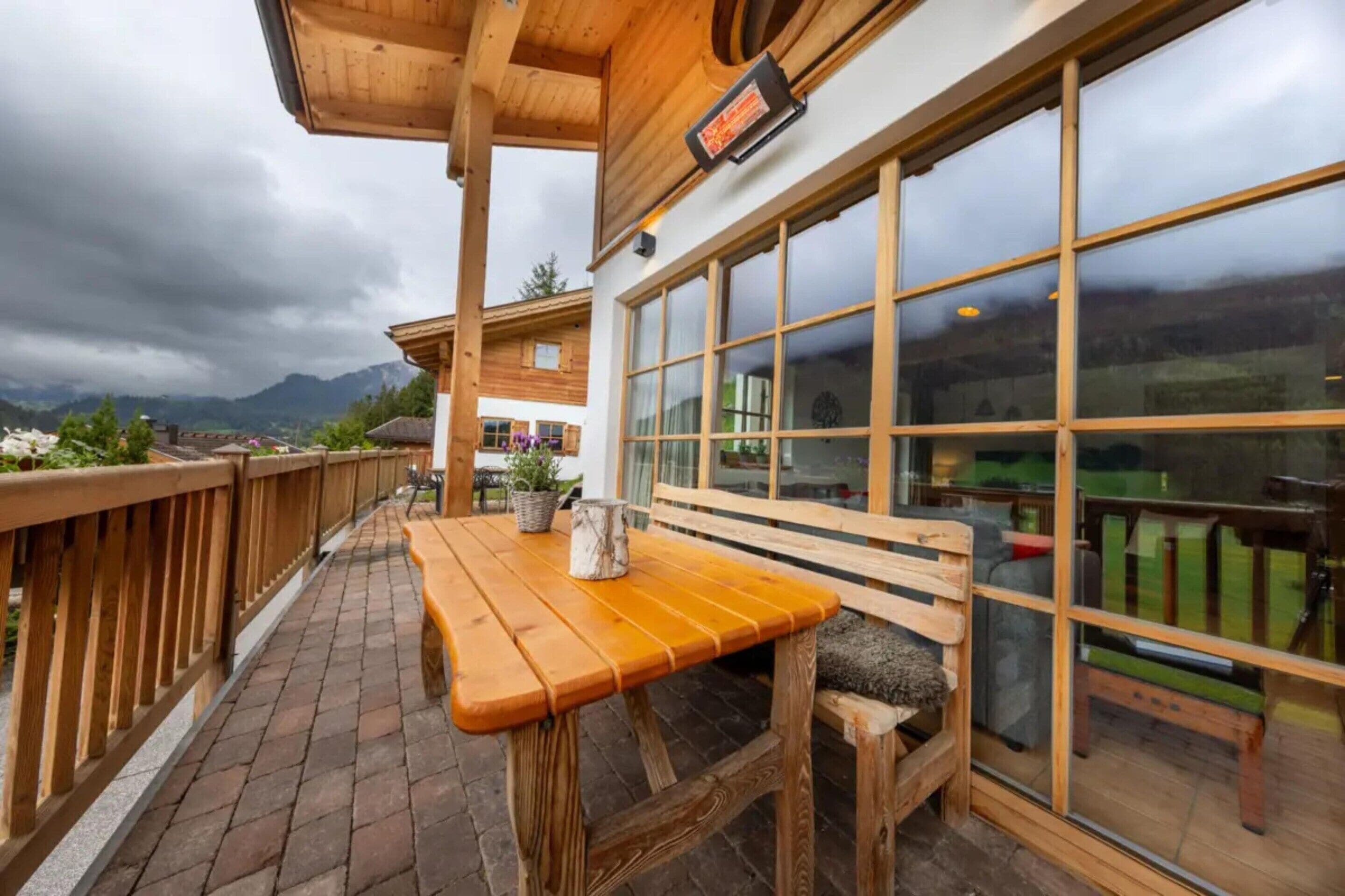 Um deck de madeira com um banco e mesa, com vista para uma paisagem montanhosa.