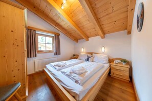 Une chambre à coucher en bois, avec un lit, des tables de chevet, une fenêtre et un radiateur.