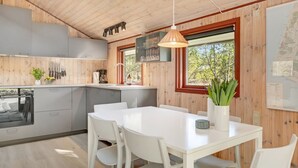 Eine moderne Küche mit Essbereich, Holzwänden und einem großen Fenster.