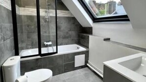 A modern bathroom with a skylight, a bathtub, a toilet, and a shower enclosure. - Apartment Saphir (5) 2/6 pers (Sedan)
