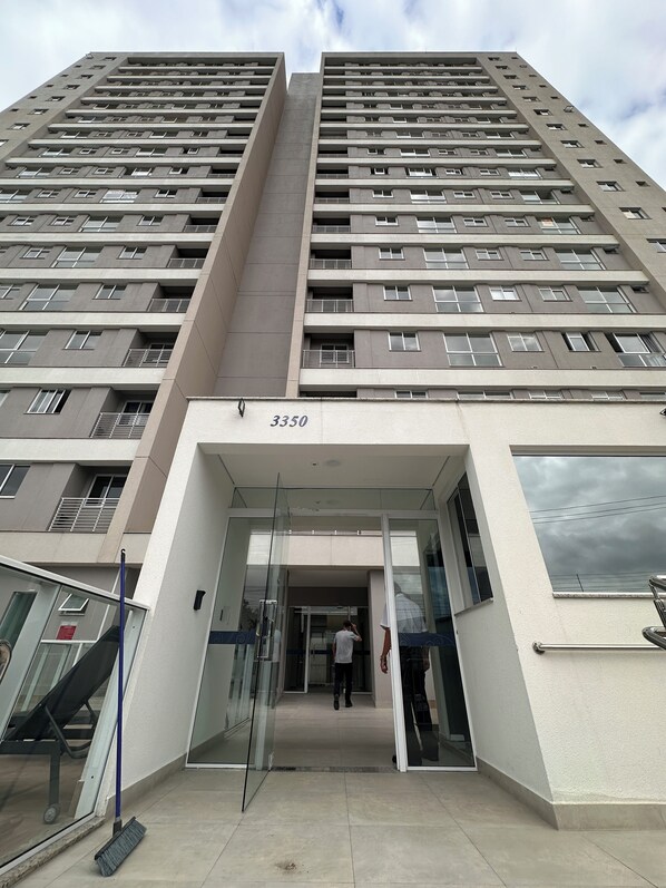 A high-rise building with a modern architectural design, featuring a prominent entrance with glass doors and a metal railing.