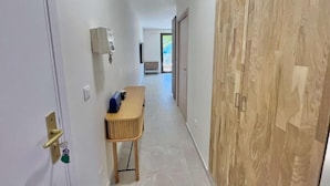 Un couloir avec une armoire en bois, une petite table avec des chaises et un luminaire fixé au mur.