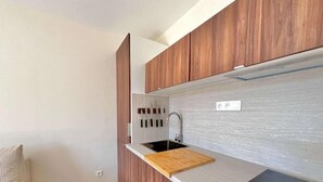 Une cuisine moderne avec des meubles en bois, un plan de travail noir et un évier encastré.