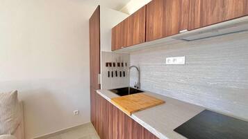 Une cuisine moderne avec des meubles en bois, un plan de travail noir et un évier encastré.