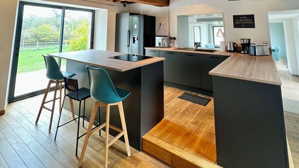 A modern kitchen with a large island, wooden beams, and a view to the outdoors. - Maison des H, by the lake (CANISY)