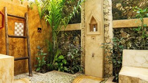 A rustic bathroom with a wooden ladder, a stone wall, and a small shelf with a bottle. - Villa Bahati Zanzibar (Jambiani)