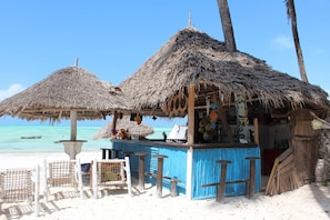 A beach bar with thatched umbrellas and a blue counter. - Villa Bahati Zanzibar (Jambiani)