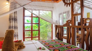 A room with a bed, a wooden partition, and a view of greenery outside. - Villa Bahati Zanzibar (Jambiani)