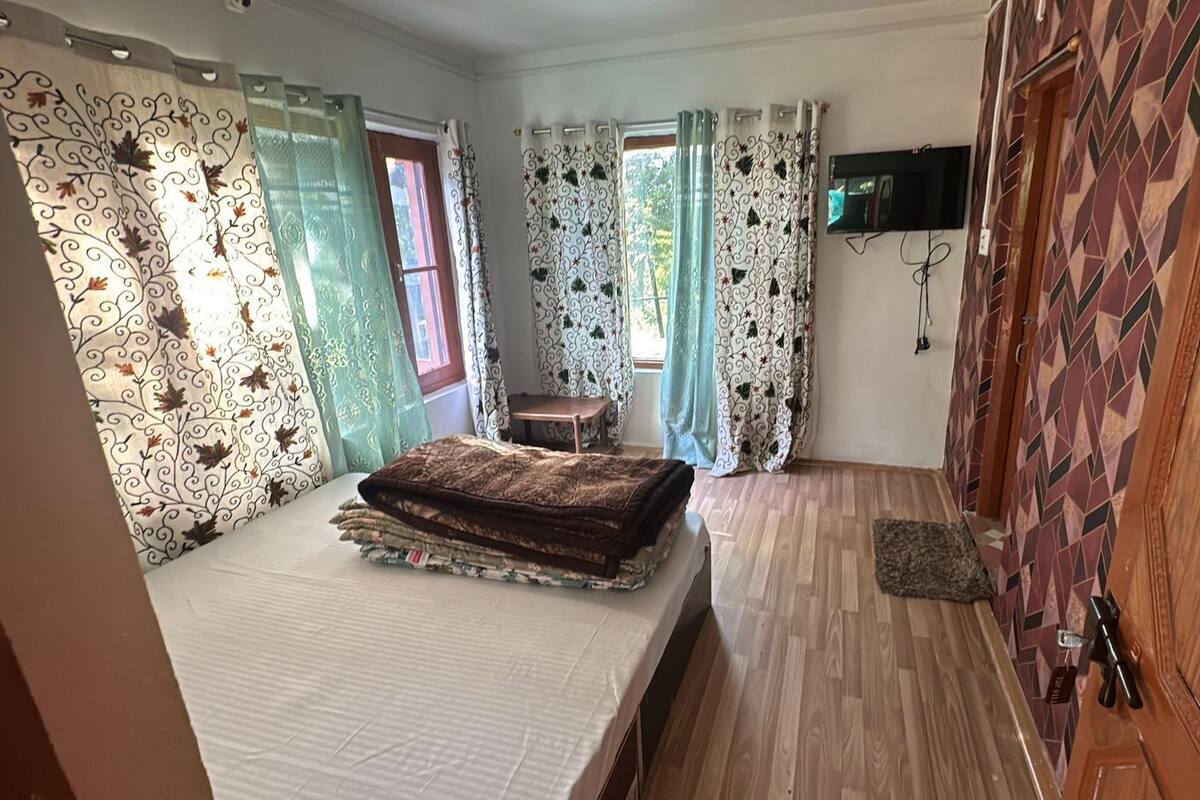 A bedroom with a bed, a TV mounted on the wall, and a patterned door.