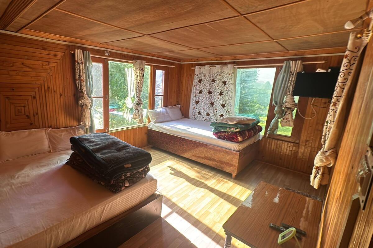 A wooden cabin room with a bed, a bench, and a small table.