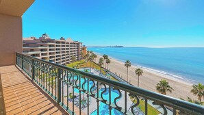 Ein Balkon mit Blick auf einen Strand, ein Schwimmbad und ein Hotelgebäude.
