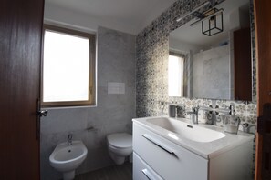A bathroom with a sink, toilet, and window. - Casa Rosada (Budoni)