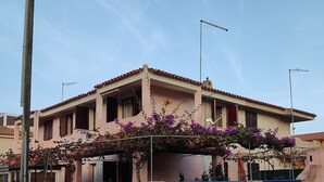 Uma casa de dois andares com varanda, antena visível e guarda-corpo azul.