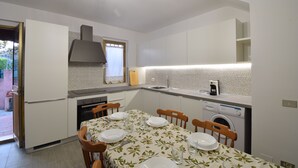 Uma cozinha moderna com armários brancos, uma mesa de jantar posta com pratos e uma máquina de lavar.