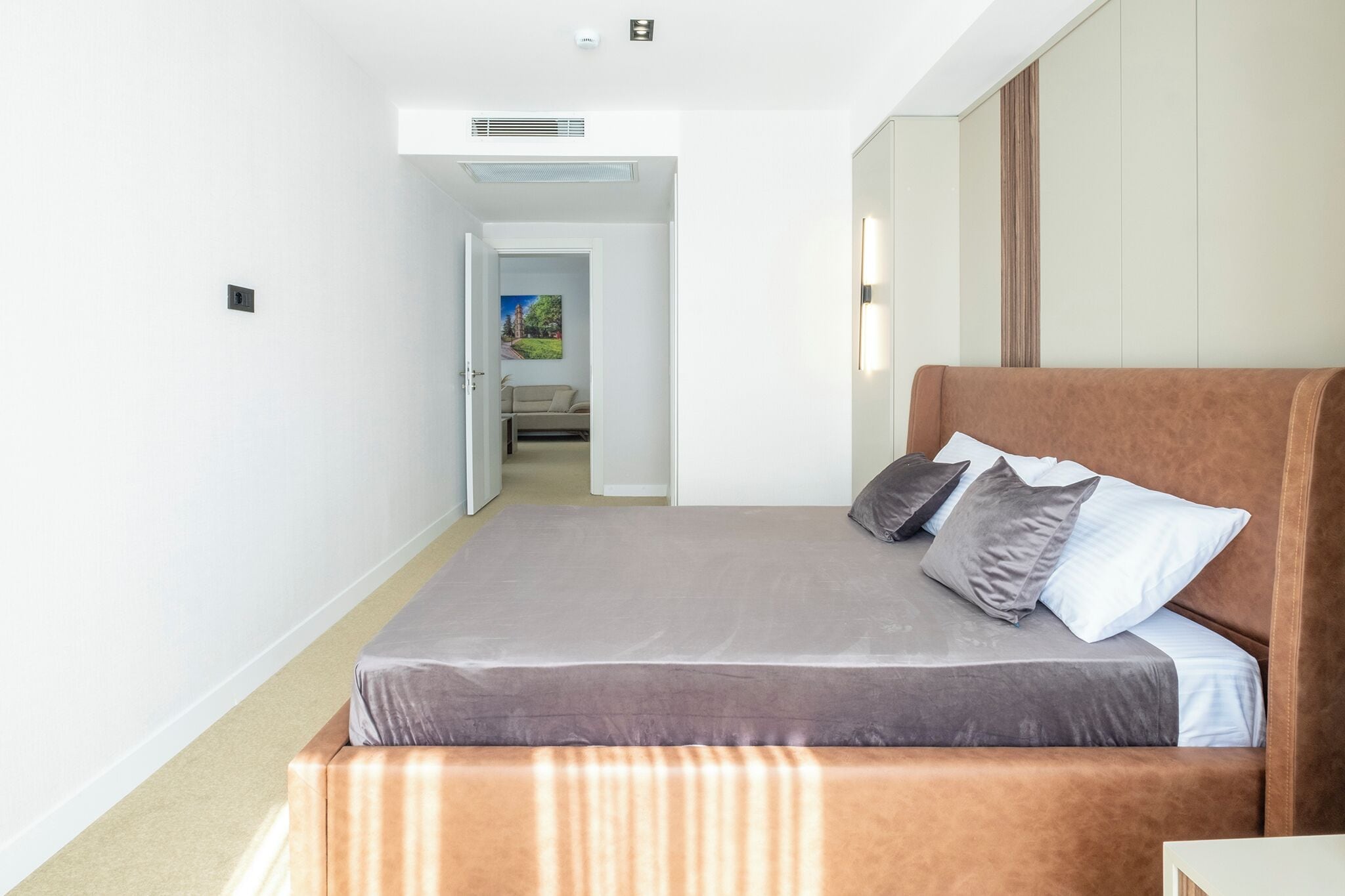 A bedroom with a large bed, a wardrobe, and a door leading to a bathroom.