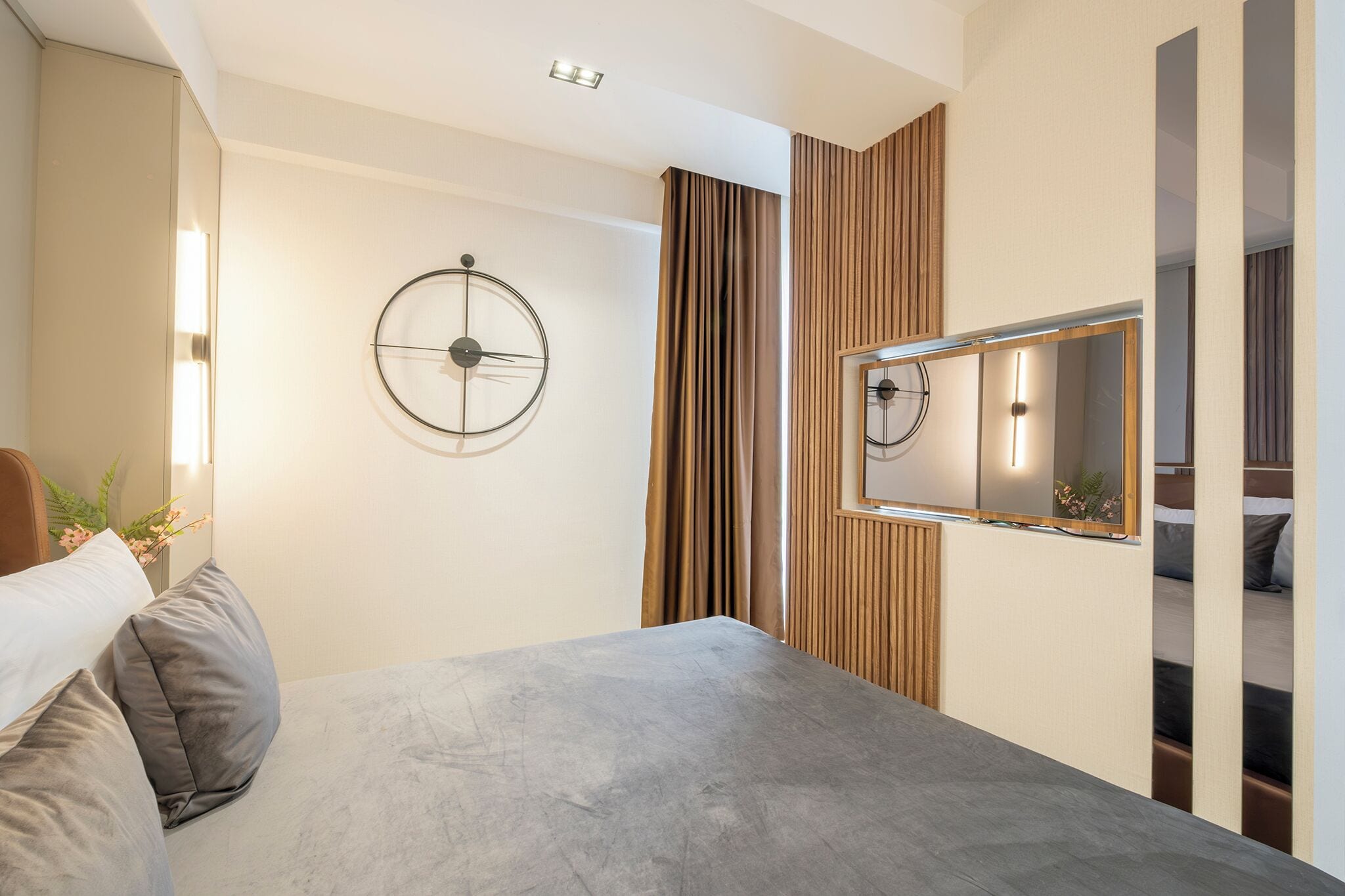 Une chambre moderne avec un grand lit, une horloge murale ronde, un miroir et un mur recouvert de panneaux en bois.