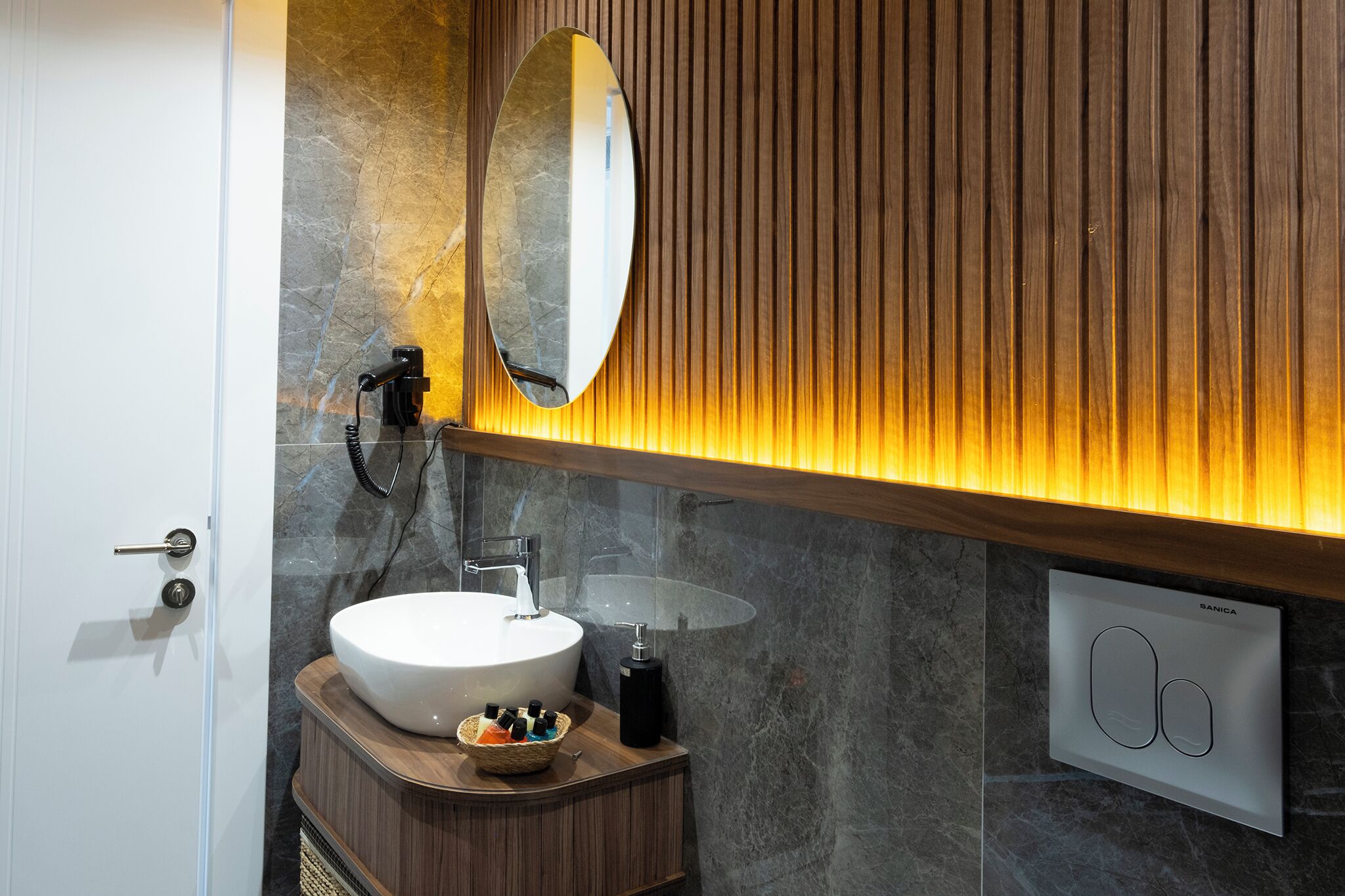 Une salle de bain moderne avec un meuble-lavabo en bois, un grand miroir ovale et un radiateur encastré.