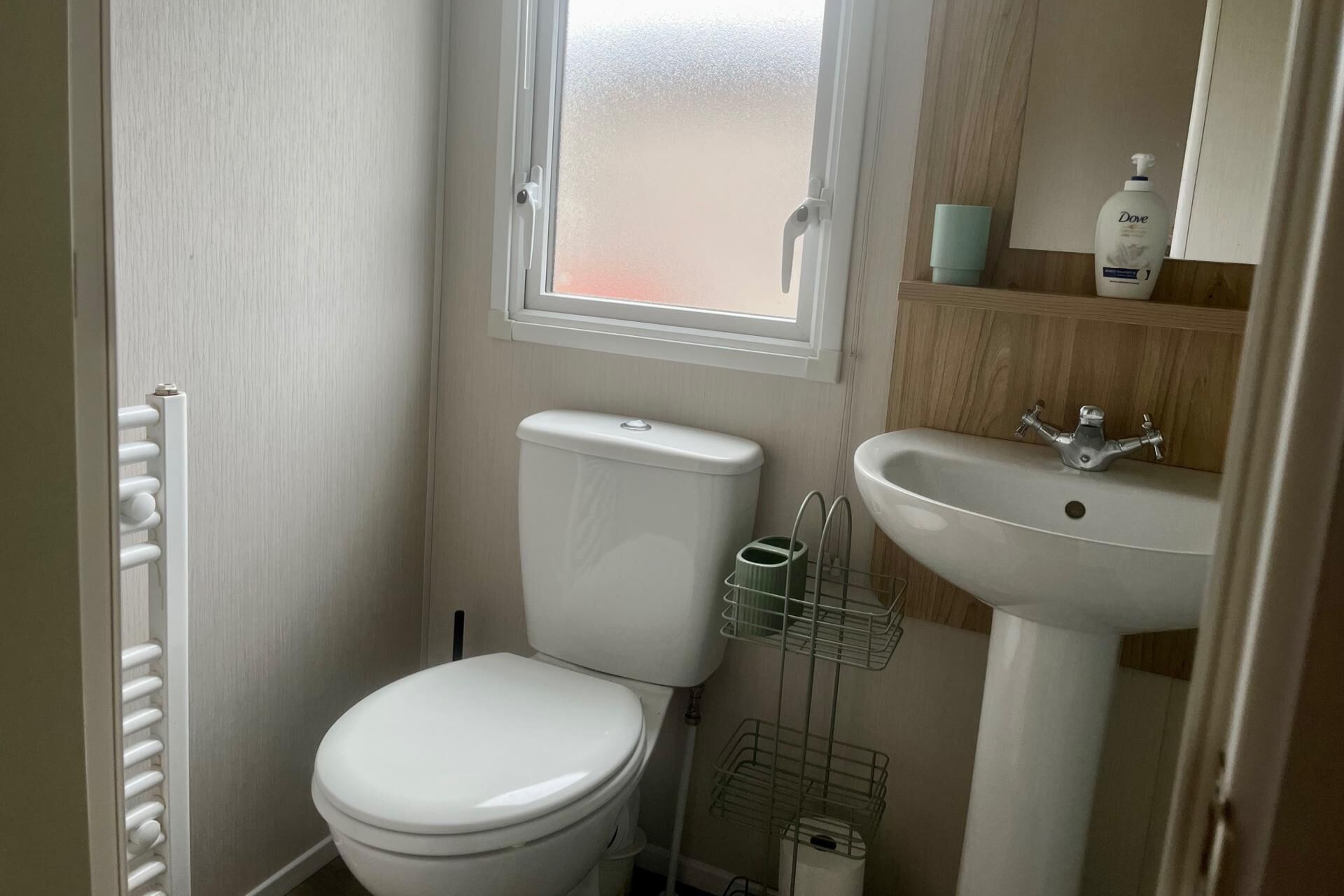 Un baño pequeño con inodoro, lavamanos y ventana.