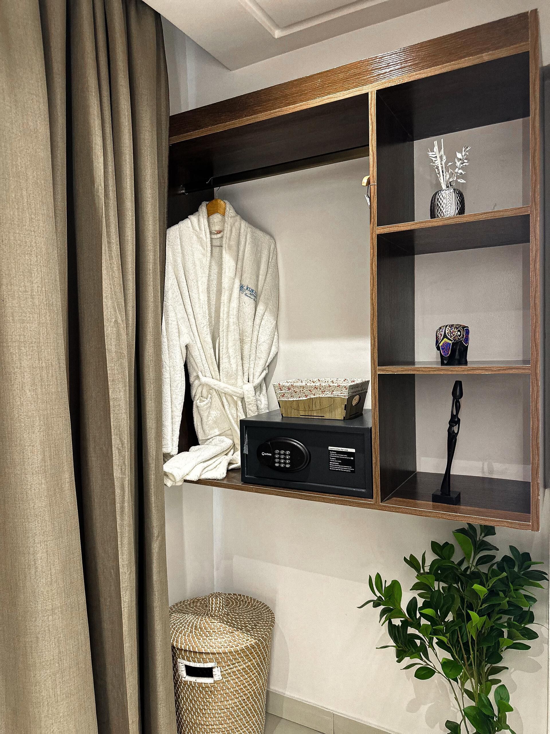 A bathroom with a robe hanging on a rack, a black radio, and a decorative item on a shelf.
