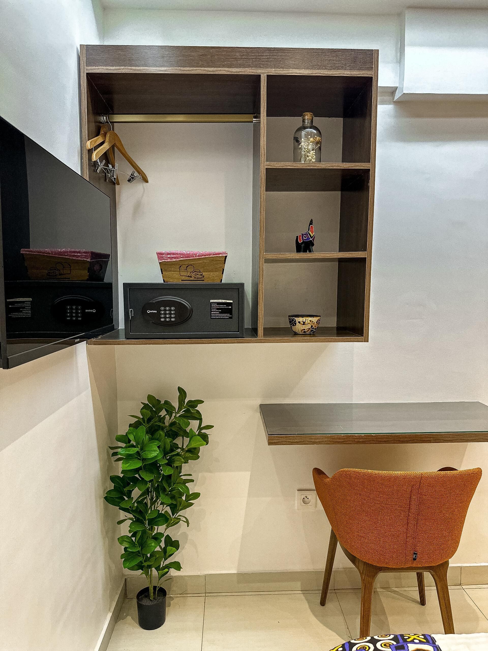 A compact kitchen with a built-in microwave, a small radio, and a shelf with decorative items.