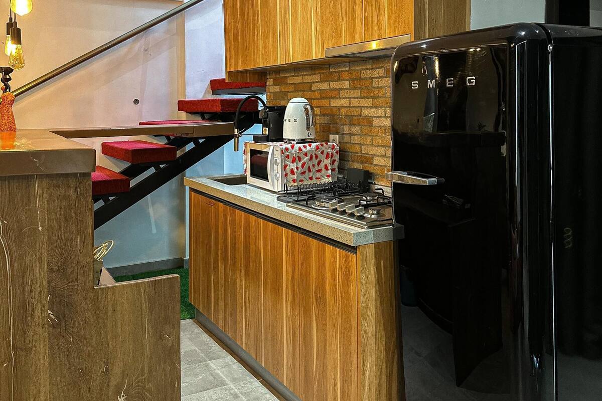 A modern kitchen with wooden cabinets, a built-in island, a black refrigerator, and a gas stove.