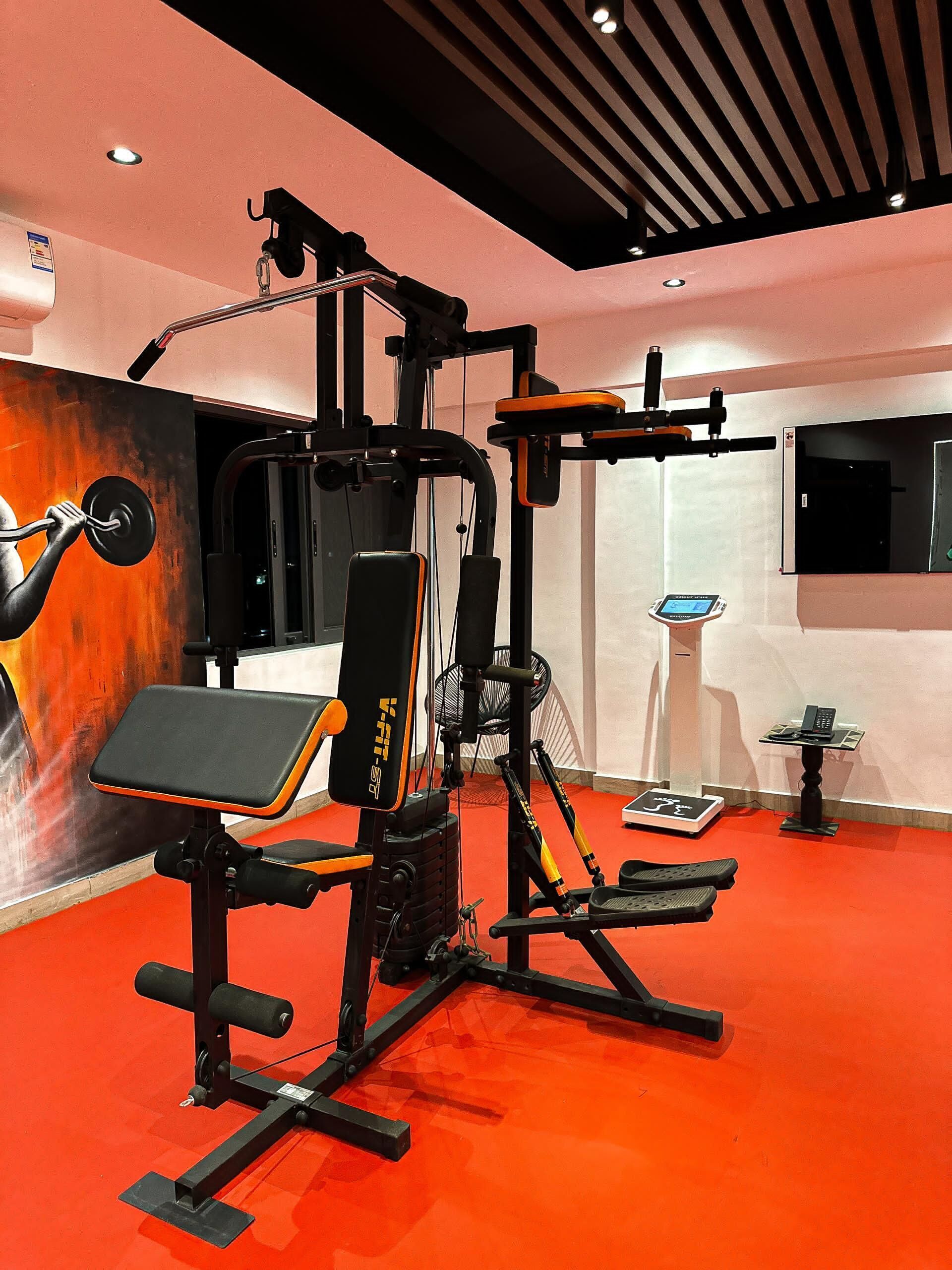 A gym with a variety of exercise equipment, including a bench press, a squat rack, and a cable machine.