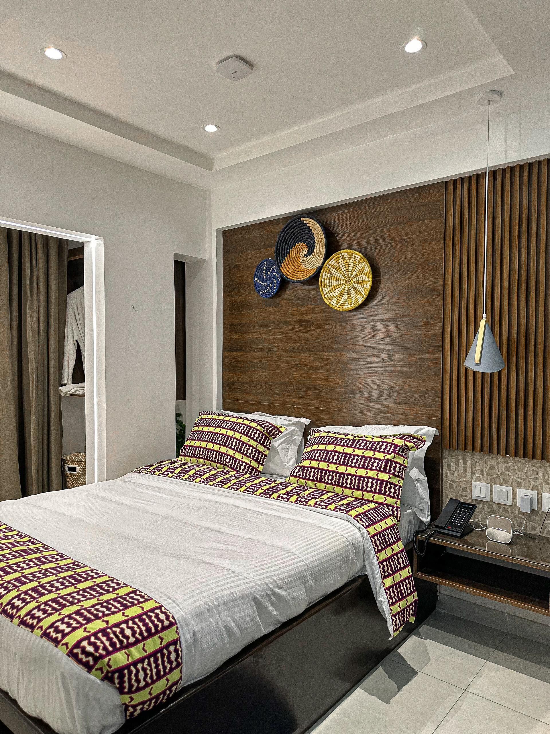 A modern bedroom with a large bed, a wooden headboard, and decorative wall art.