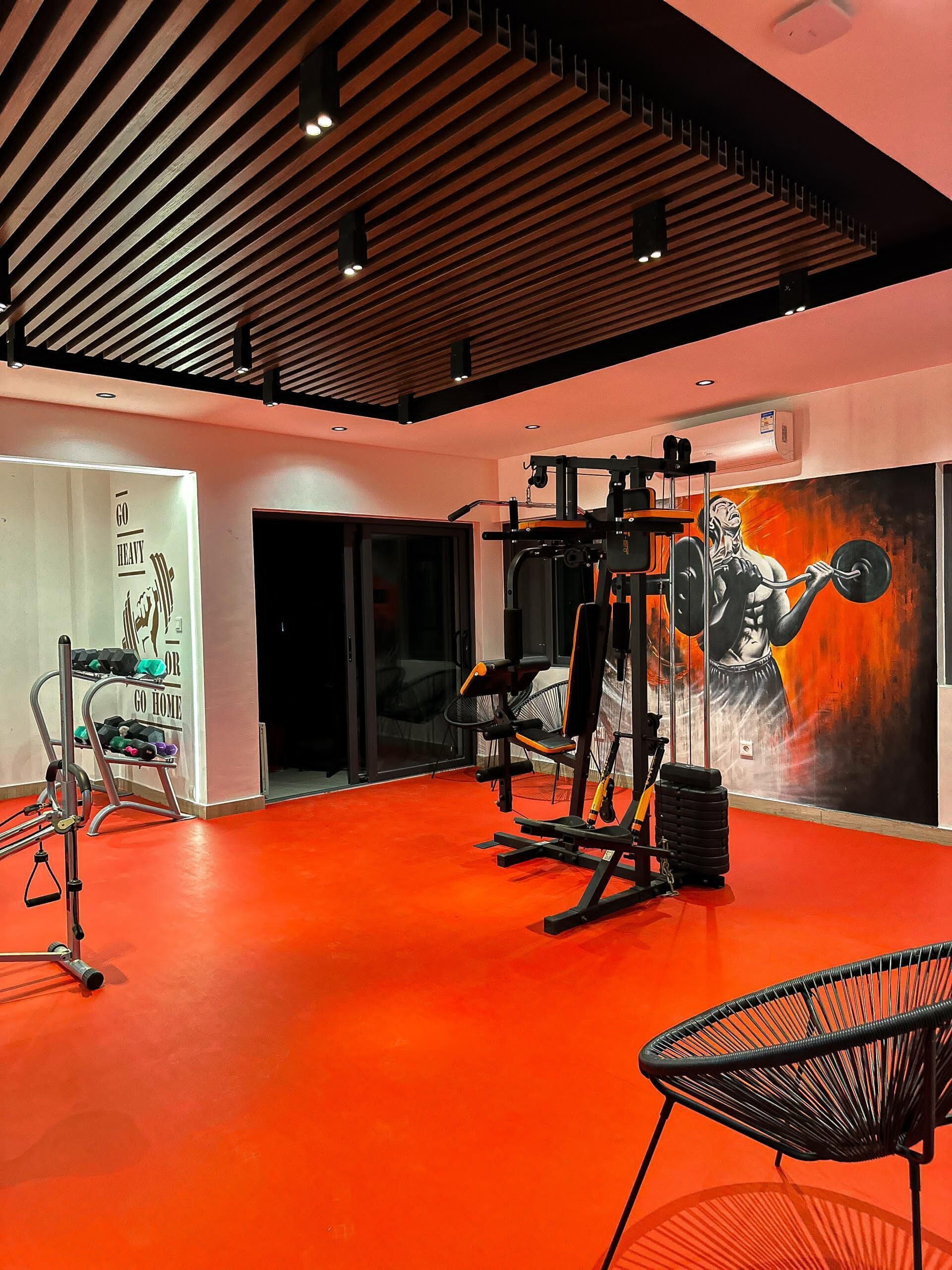 A gym with exercise equipment, a mural, and a red floor.