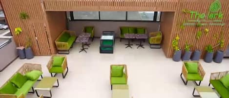 Un área de lounge en la azotea con asientos acolchados verdes, una mesa de centro y plantas en macetas.