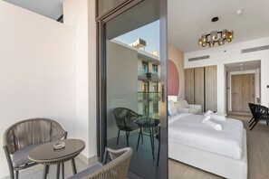 Een moderne hotelkamer met balkon, een bed met witte lakens, een glazen deur naar een balkon en een moderne kroonluchter.