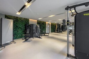 Een sportschool met diverse fitnessapparaten, waaronder een squatrek en gewichtmachines.