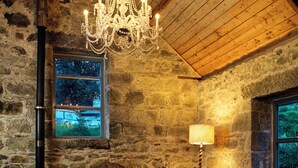 A rustic stone interior with a fireplace, a chandelier, and cozy furnishings. - Crab Lane Studios (Shillelagh)