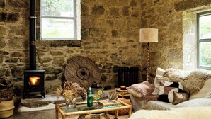A rustic stone interior with a wooden ceiling, a chandelier, a stone fireplace, and a cozy seating area. - Crab Lane Studios (Shillelagh)
