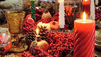 Une table décorée de bougies, d’une grenade et de baies rouges, évoquant une ambiance festive ou de fêtes.