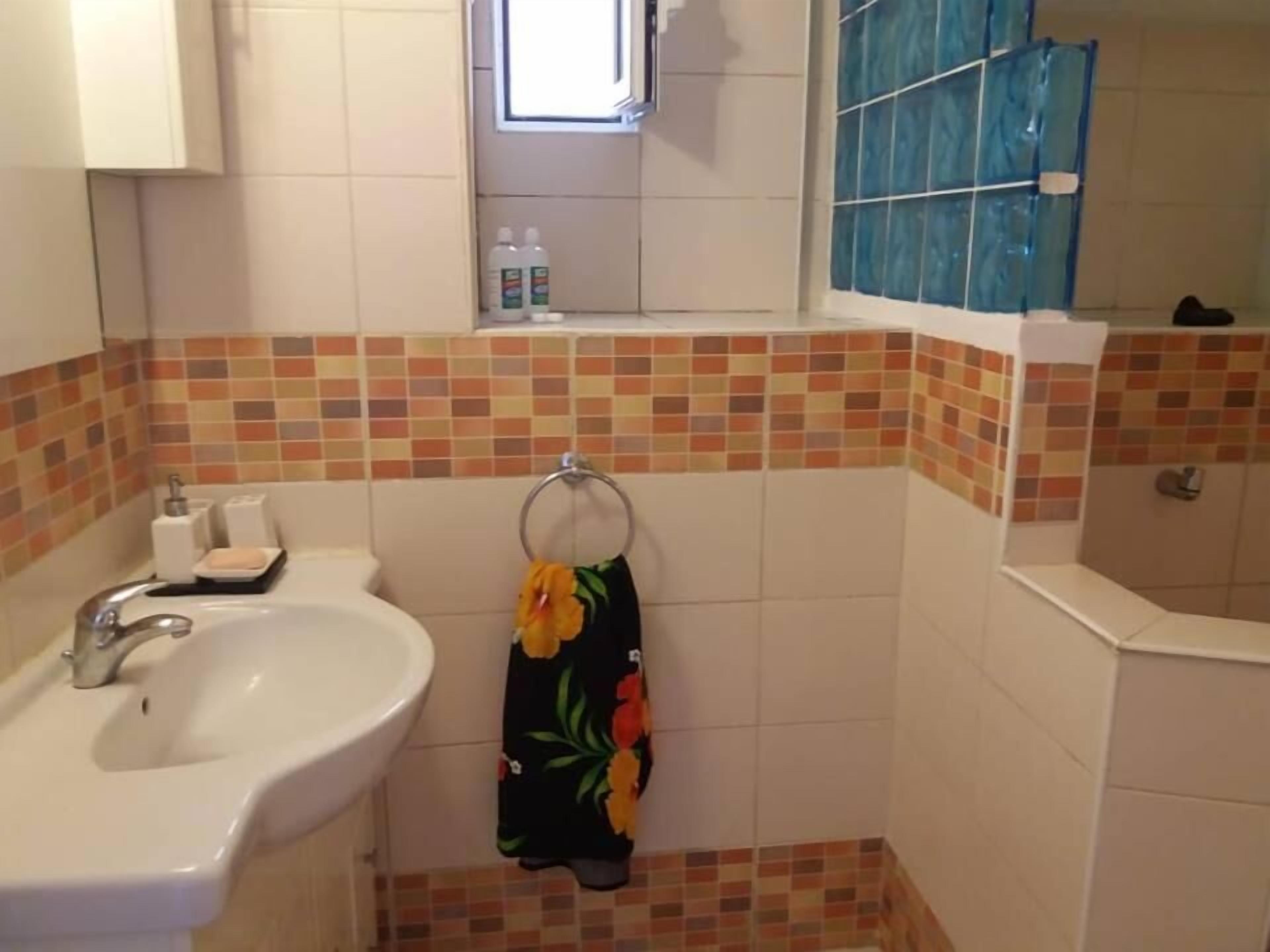Un baño con lavamanos, espejo y ducha.