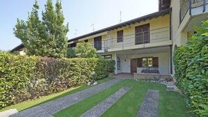 Ein zweistöckiges Gebäude mit Balkon, gepflegtem Rasen und Hecke.