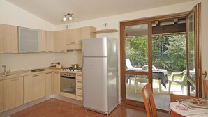 Eine Küche mit Holzausstattung, einem Edelstahlkühlschrank, einem Herd und einem Essbereich mit Tisch und Stühlen.