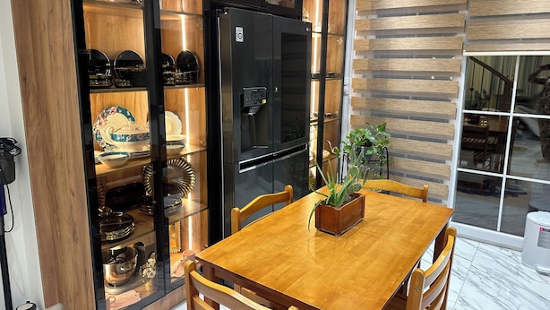 A modern kitchen with a built-in black refrigerator, wooden cabinetry, and a dining table with chairs. - Luxury apartment f4 with terrace on 2 floors in a private residence El Achour (El Achour)