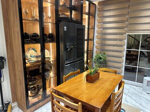 Une cuisine moderne dotée d’un réfrigérateur noir encastré, de meubles de rangement en bois et d’une table à manger avec des chaises.