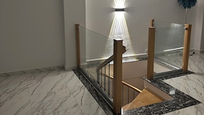 A modern interior with a marble floor, a glass railing staircase, and a ceiling light fixture. - Luxury apartment f4 with terrace on 2 floors in a private residence El Achour (El Achour)