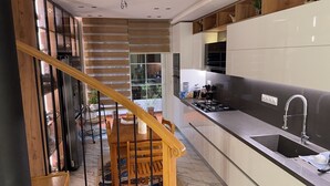 A modern kitchen with a wooden staircase, a dining area with a table and chairs, and a large window overlooking the outdoors. - Luxury apartment f4 with terrace on 2 floors in a private residence El Achour (El Achour)