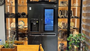A modern kitchen with a black refrigerator, a water dispenser, and various kitchenware on shelves. - Luxury apartment f4 with terrace on 2 floors in a private residence El Achour (El Achour)